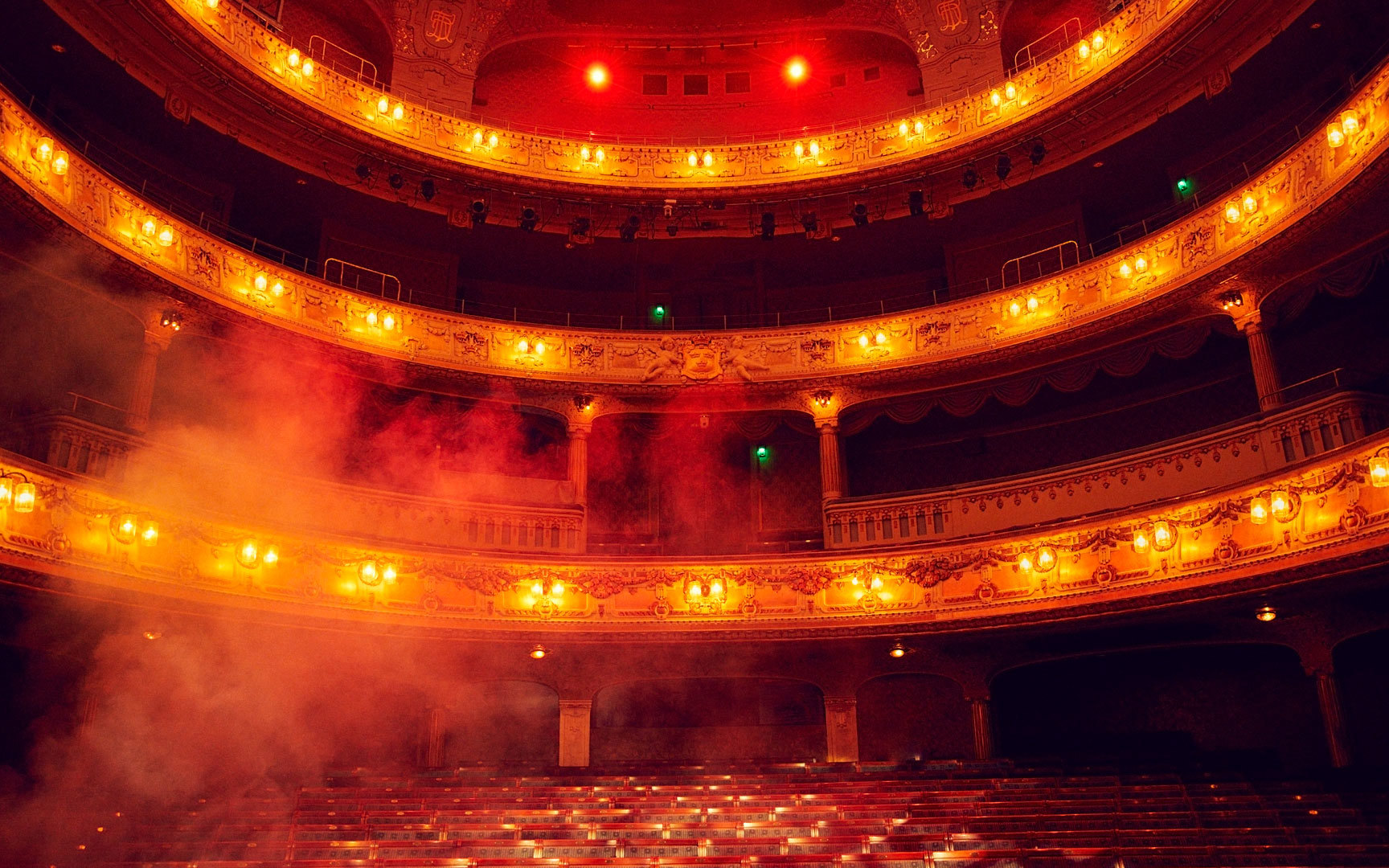 Rök ligger över Stora scenen som är upplyst i rött.